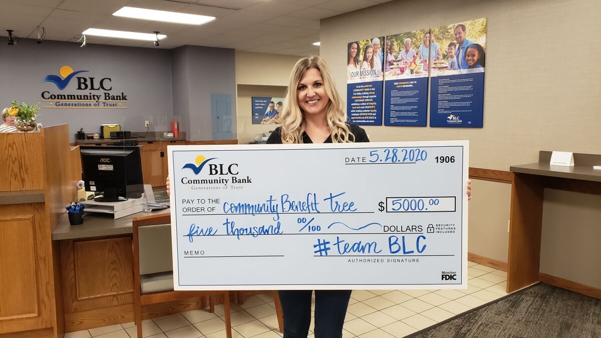 Holly shows off a big check from BLC Community Bank to Community Benefit Tree.